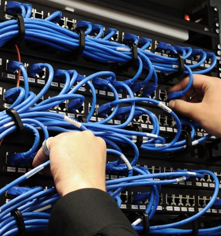 Network server with blue ethernet cables being installed by disembodied hands